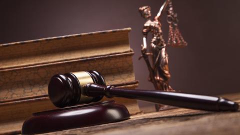 judges gavel on a desk in front of law books and a scales of justice 